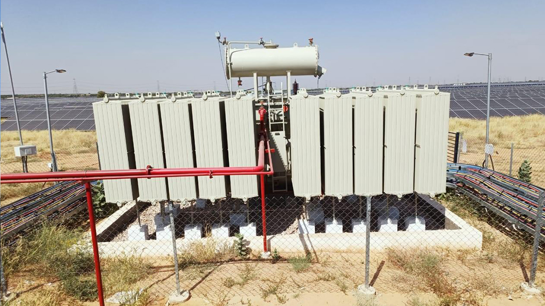Dubai Warehouse Solar Transformer Selection: Reverse Power and Connection Capacity 6 Oil-immersed transformer with radiator banks and a conservator beside rows of ground-mounted solar panels