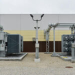 Two oil-immersed transformers with cooling fans installed beside an industrial building
