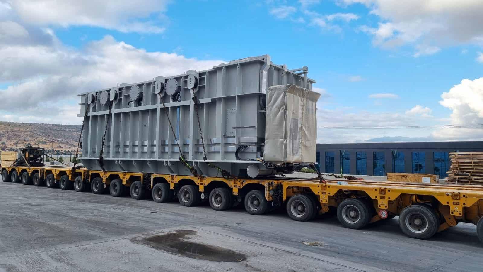 Large transformer secured with chains on a yellow multi-axle transport trailer