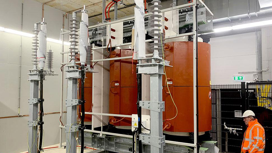 Indoor dry-type transformer with orange windings and a technician nearby