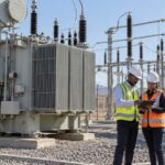 Engineers reviewing a South African industrial transformer tender beside an outdoor power transformer